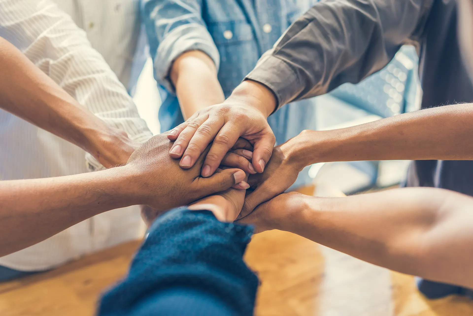 A diverse group of people stacking their hands together in a sign of teamwork, collaboration, and unity.