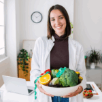 A nutritionist holds a bowl of fruit in her office.