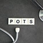 Word “POTS” written on letter tiles next to a medical tool. 