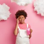 A woman grabs her head with clouds around her, symbolizing brain fog.