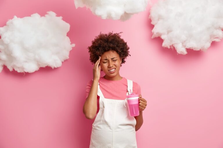 A woman grabs her head with clouds around her, symbolizing brain fog.