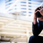 A stressed-out businessman puts his head in his hands while dealing with anxiety.