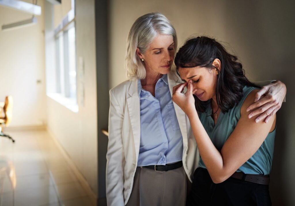 A therapist gently supporting a grieving woman during an emotional session